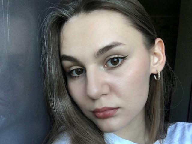 SofinaNash hat eine blasse Haut, braune Augen mit dicker schwarzer Eyeliner und eine leicht zusammengezogene Stirn. Sie trägt einen kleinen Ohrring und hat glattes, braunes Haar. Ihre Brüste sind nicht sichtbar..