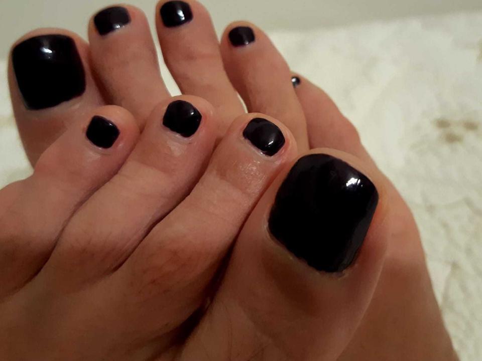 YaraSweet's feet with shiny black nail polish on each toe, her toes slightly curled together, showing off her polished, glossy toes in the foreground.