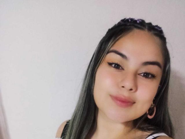 YeiliSweet with long black hair, brown eyes, and a subtle smile, wearing hoop earrings, looking slightly to the side with a soft, slightly flushed face.