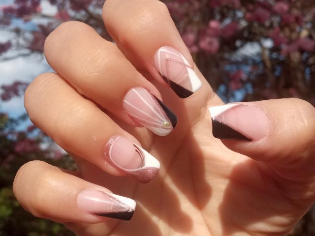 LanaLorens' hand with glossy pink nails, black and white tips, and subtle glitter, showing off her sexy, well-manicured, sexy-ass nails in bright sunlight.