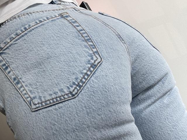 Sandras Hintern in engen, hellblauen Jeans, die eine Gesäßtasche und ihre Pobacken zeigen, mit einem leicht strukturierten, ausgeblichenen Stoff. Aufgenommen aus einem niedrigen Winkel..