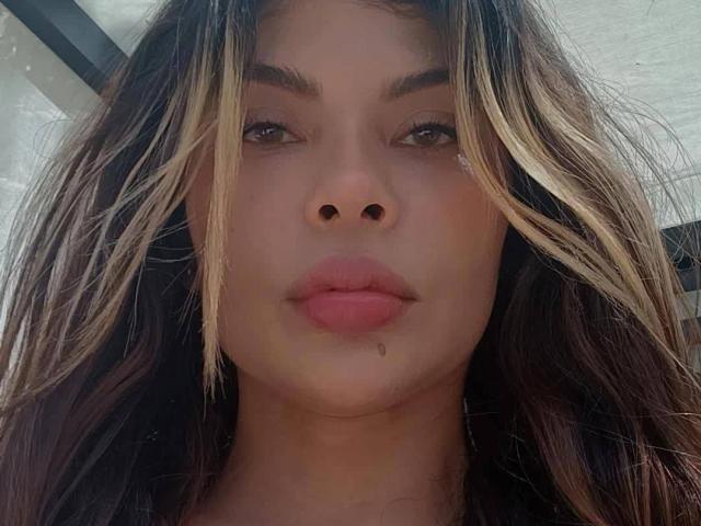 JulieGambel's face with blonde highlights in her brown hair, full pink lips, small black nose, and a slight black hair follicle near her chin. She looks directly at camera.