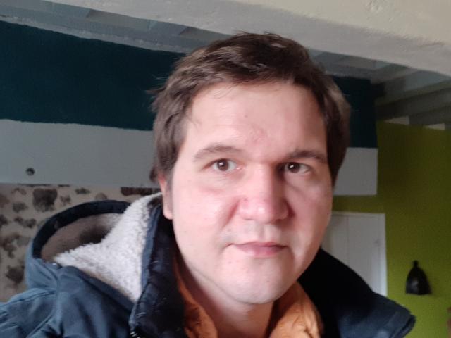 NectarineFad has a chubby face, short brown hair, light skin, and is wearing a dark blue puffy jacket with a white fuzzy hood. His nose is slightly red.