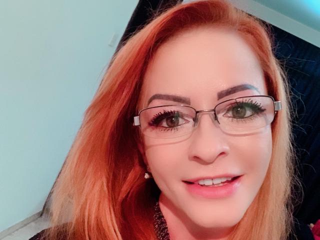 Cette enseignante69 a les cheveux roux, des lunettes et un sourire charmant. Elle met en valeur ses yeux verts et ses lèvres roses. Ses seins ne sont pas visibles sur cette image..