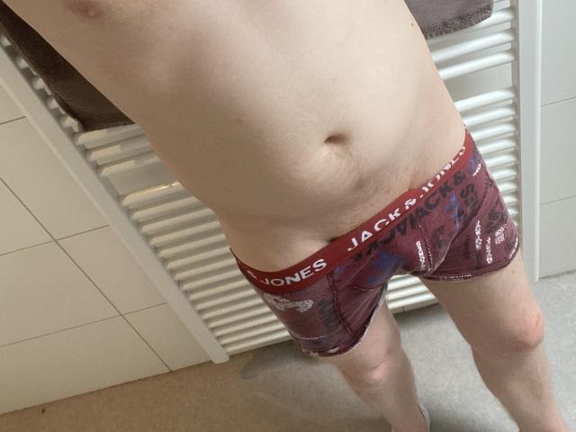 Koentjes blasse Haut, leicht rundlicher Bauch und rote Boxershorts mit dem Schriftzug "Jack Jones" am Bund, er steht mit gespreizten Beinen in einem Badezimmer. Koentjes nackte Brust, keine sichtbaren Genitalien..
