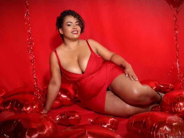 SammyHank with curly black hair, red dress, large tits, lying on red heart-shaped balloons, smiling, red background, red ribbon, curvy, sexy, confident, red heels, sexy pose.