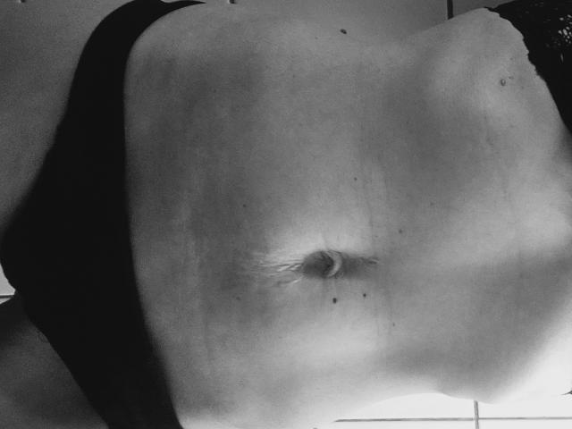 Le ventre nu et légèrement incurvé d'ApoloniaRed, avec un nombril visible, portant des sous-vêtements sombres, sur une photo en noir et blanc. La peau d'ApoloniaRed présente de petites taches de rousseur et une texture douce et claire..