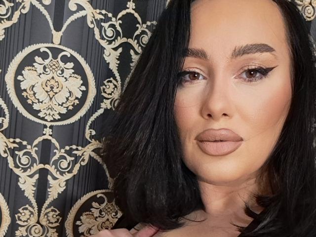 AnnaElyse has black hair, brown eyes, and full, pouty lips with subtle makeup. Her eyebrows are dark and shaped, and she's looking directly at the camera.