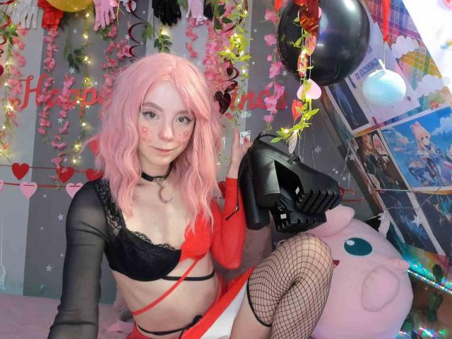 MissAstravert with pink hair, black lace bra, red and black top, fishnet stockings, black mask, holding mask, pink wig, choker, cute face, small tits, bedroom, colorful balloons.