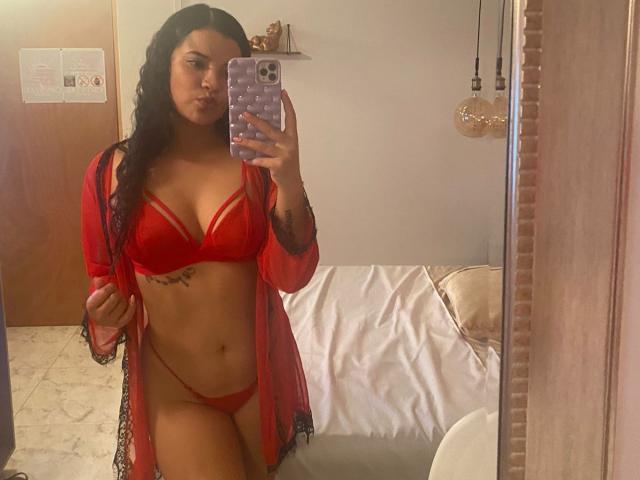 DannaMiler in red lingerie, showing her tits and pussy in a mirror selfie. She has a tattoo under her right boob, wearing a sheer red robe.
