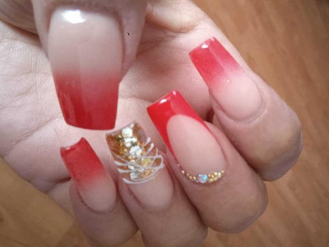 LizaRussell's nails are red with gradient tips, one nail has gold and white sequins, another has tiny multicolored gems. Boobs are not visible.
