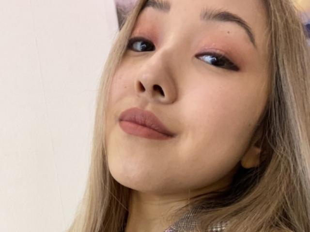 RenyLime has light brown skin, blonde hair, and is smiling with pinkish-brown lipstick and subtle eye makeup. Her eyebrows are thin and she's looking slightly up.