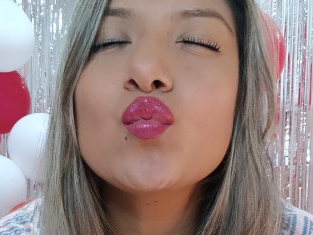 ValeriaHunter69's puffy pink lips are puckered in a kiss, eyes closed, with long eyelashes and light brown hair. She has a small mole below her nose.