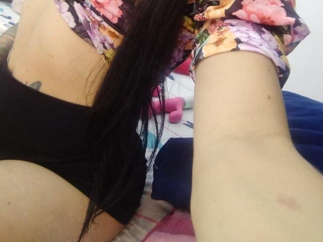 SaoryPrincess's long black hair, floral shirt, and black panties, showing her ass and a small tattoo on her left side, with a visible arm in the foreground.