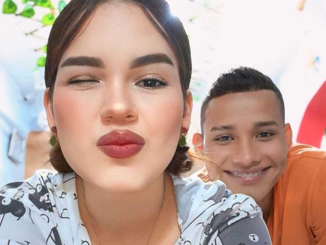 MorenoAndNayla's face is front and center, winking with red lipstick, while a cute boy with short hair and an orange shirt leans in smiling behind her.