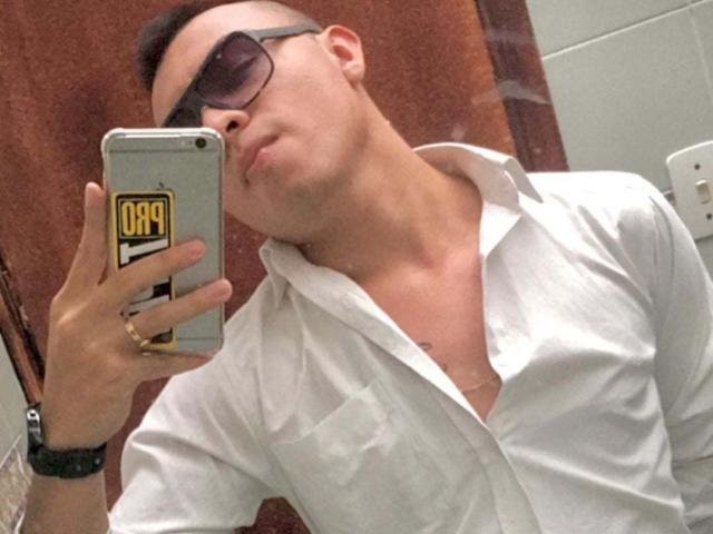 JaneAndPaull with a shaved head, wearing sunglasses, a white button-down shirt, and a gold ring, taking a selfie with a phone, pouting slightly.