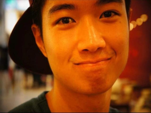 Una foto di ChristopherLongest con un leggero sorriso, occhi marroni e un cappello nero, che indossa una camicia verde, con un viso carino e da ragazzo e una piccola area di barba incolta..