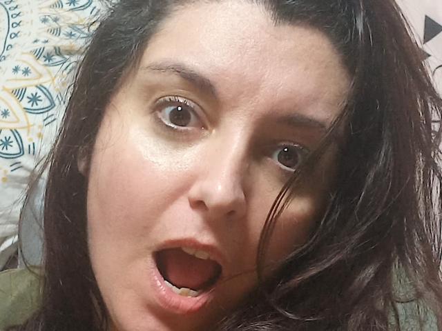 La Française Jessy a les yeux marron, les lèvres légèrement entrouvertes et les cheveux noirs et ondulés, avec une expression de surprise et la bouche ouverte. Sa peau est claire avec quelques taches de rousseur..