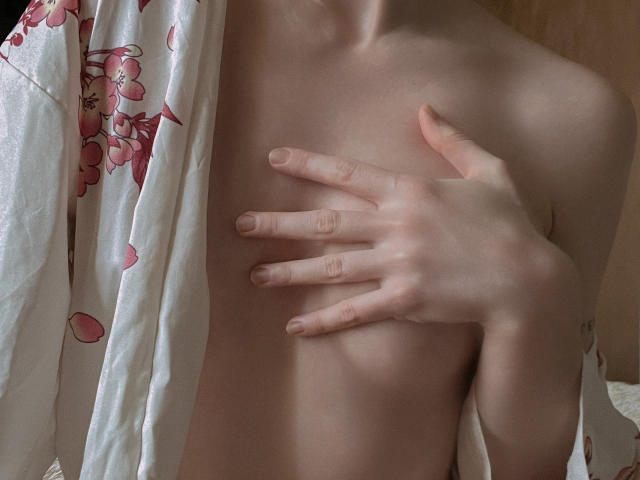 JaneRoller's bare chest with a hand covering her small tits. She's wearing a floral kimono, her skin is pale, and her fingers are slightly spread.