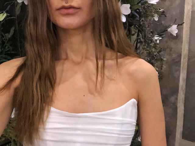 Karish with long brown hair, nose piercing, white strapless top, showing collarbone and upper chest, small tits, subtle ass, light skin, slightly parted lips.