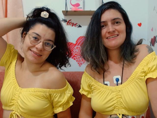 LunaVenus has curly black hair, glasses, and yellow off-shoulder tops, showing her tits and smiling. Another LunaVenus with wavy black hair, yellow top, and tattoo, smiles.