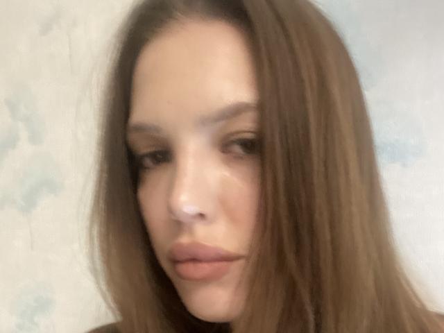 KateMariett's face with brown hair, soft brown eyes, and slightly parted pinkish lips, blurred slightly, showing a subtle, relaxed expression. She has a fair skin tone.