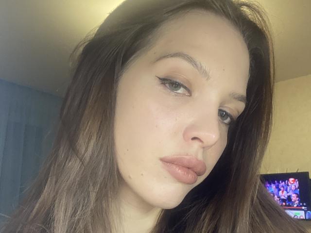 KateMariett hat eine blasse Haut, braune Augen und volle, rosafarbene Lippen mit dezentem, geschwungenem Eyeliner. Sie hat langes, braunes Haar, eine kleine Nase und einen leicht ernsten Gesichtsausdruck..