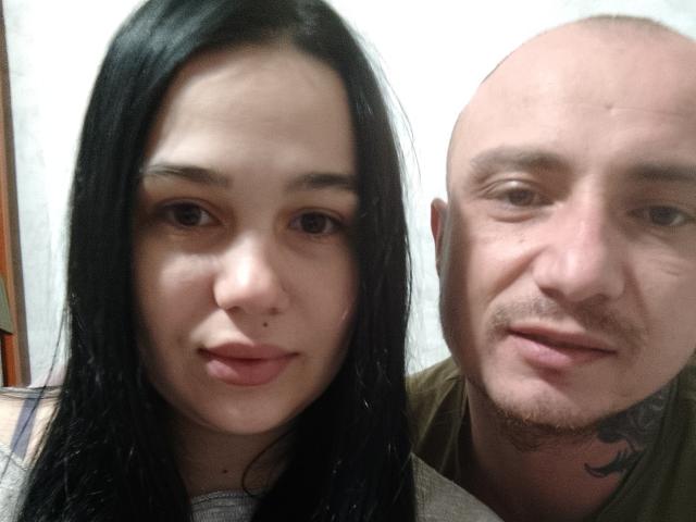 DaraCpl tem cabelo preto, um nariz pequeno e uma pinta no rosto. Ao lado dela, está DaraCpl careca, com barba e tatuagem, sorrindo..