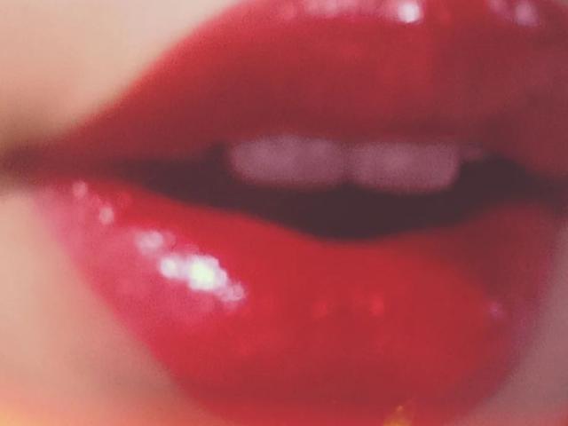 Yukio's shiny red lips are in the center, slightly parted to reveal white teeth. The glossy texture makes the lips look plump and seductive.