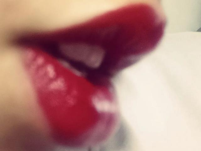 Yukio's glossy red lips are slightly parted, showing a small white tooth. Her shiny red lipstick is smeared, adding a sensual touch to her pouty expression.