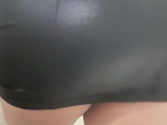Barbarica's black leather skirt is tight, highlighting her round, bare ass. The material is shiny, reflecting light. Her pale skin is visible at the bottom edge.