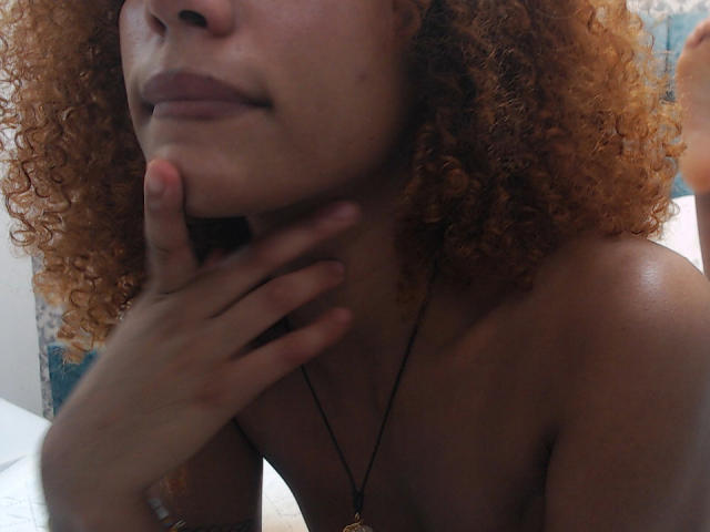 CinthiaWalker has curly orange hair, a hand under her chin, and is topless with a necklace. Her lips are slightly parted, showing a subtle, relaxed expression.