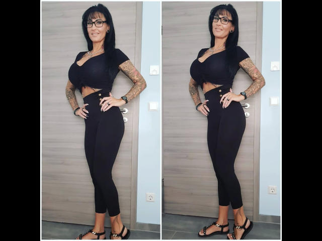 Sari-Sander has big tits, black cropped top, high-waisted black pants, tattoos on arms, glasses, black sandals, standing, smiling, double image, hands on hips.
