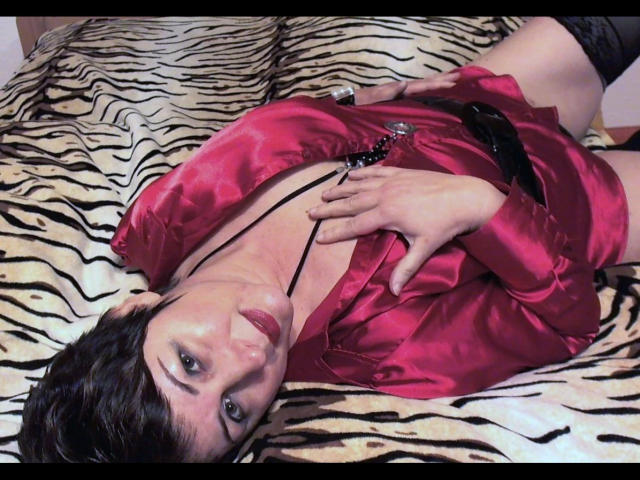 LadyElina-hot with short black hair, red satin shirt, black lace thigh-highs, lying on zebra-patterned bed, hand on chest, black necklace, red lipstick, looking up, medium tits.