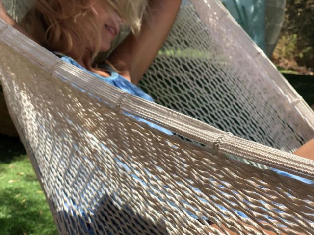 ShaiyaShy-hot's ass is in a white, knitted hammock, with blonde hair falling over her face. She's wearing a blue top, and the hammock's texture is visible.