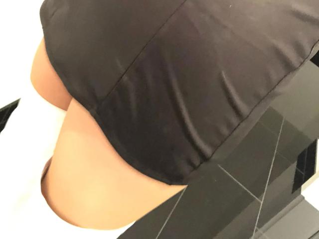 Sekretaerin41-hot's black dress is pulled up, revealing her round, tan-skinned ass and white thigh-highs, with black tiled floor visible on the right.