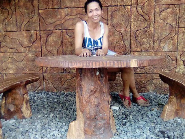 xUrDestinyTS69x-hot sitting at a rustic wooden table with a round top, wearing a blue and white tank top, red sandals, and a smile, on a gravel floor.