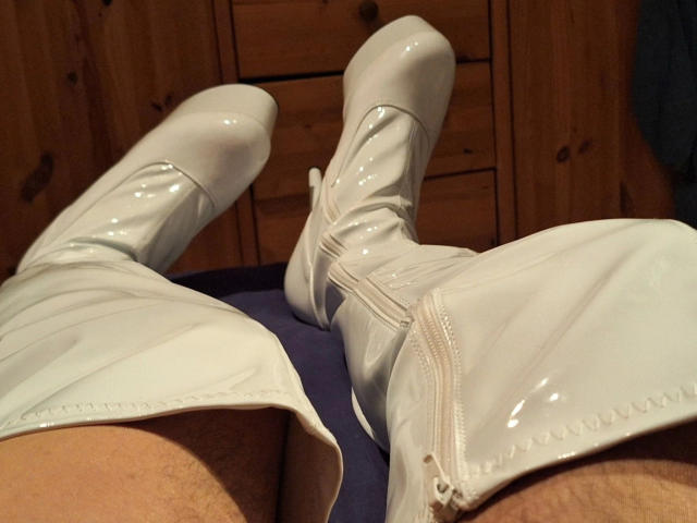 Bootsica-hot's shiny white, glossy, patent leather boots are up, showing her legs with a bit of hairy skin at the bottom. Her boots are strapped, standing out.