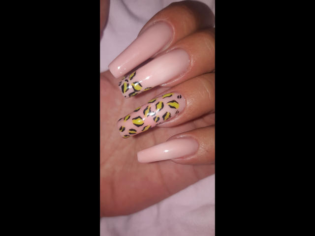 Kostlich-hot's nails are long and glossy with pink polish, featuring yellow and black leopard print on the middle and ring fingers.