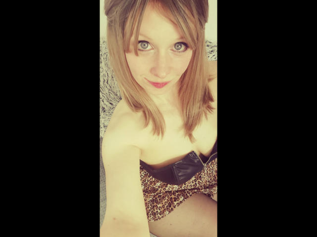 Annekehot-sex with blonde hair, green eyes, and a cute smile, wearing a strapless leopard print outfit with a black bow, showing her small boobs and slim arms.