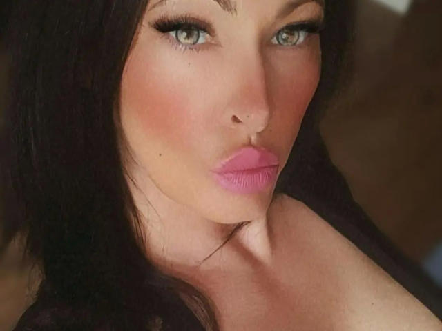 TaliaVaiolet-hot with pink lips, black hair, and green eyes, pouting her full, glossy pink lips. She's looking directly at the camera with a slight, sexy, seductive smile.