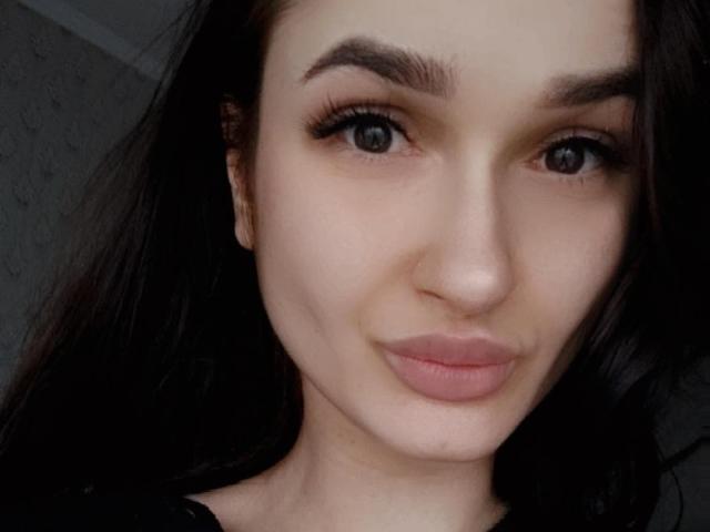 KerryB heeft vol, gladde borsten, volle, roze lippen, donkerbruine ogen en dikke, zwarte wenkbrauwen. Haar lange, bruine haar omlijst haar bleke gezicht op deze selfie..
