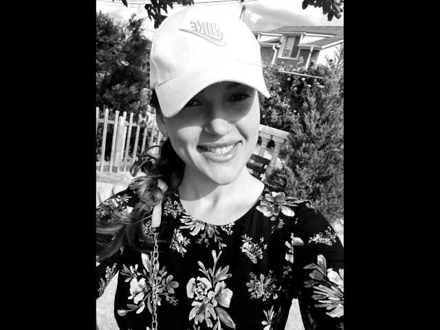 Black-and-white photo of Xxjessa-hot with a smile, wearing a floral dress and a white baseball cap, showing her tits slightly, in an outdoor setting with trees.