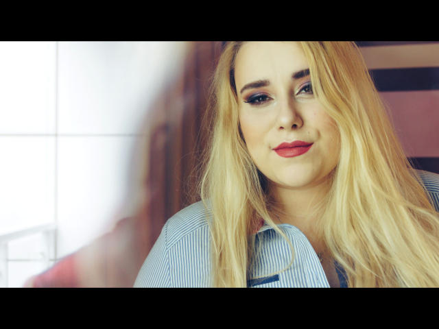 HaileyBLONDE-hot with blonde hair, blue eyes, and red lipstick, wearing a blue striped shirt, smiling slightly, with soft light on the right side of her face.