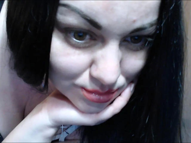 YourErica-hot has pale skin, dark wet hair, and is leaning in with her hand near her chin, showing red lips and a slight smile. Her eyes are focused.