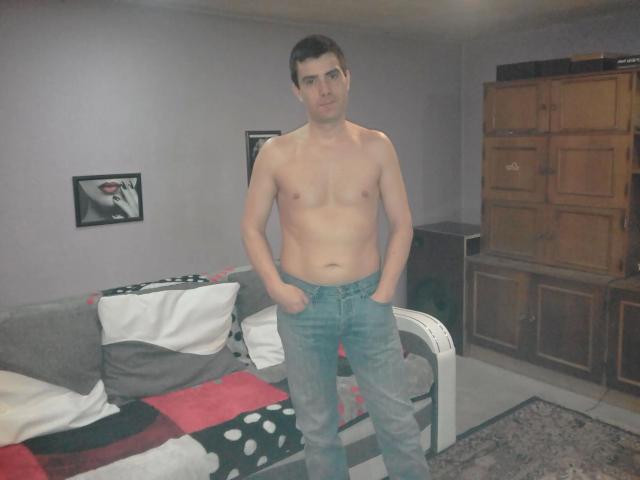 Shirtless bobandchris33-hot with hands in blue jeans, standing in a room. Bobandchris33-hot has short dark hair, glasses, and a slightly confused expression.