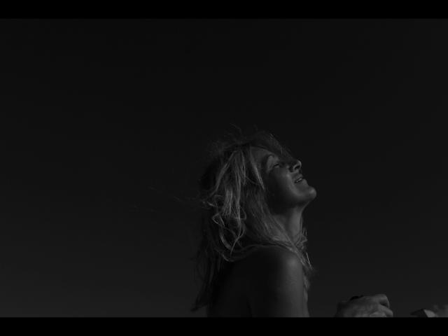 Lulu-4-you's face is turned up, eyes closed, with messy blonde hair and a slight smile. Her bare shoulders are visible, and she's in a dark, moody photograph.