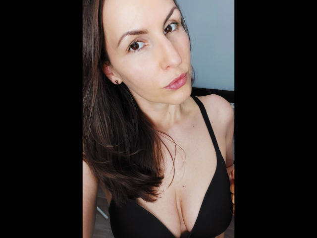 Schneewitchen1-hot with medium tits in a black bra, brown hair, light skin, pink lips, and brown eyes, looking at the camera with a slight smile.