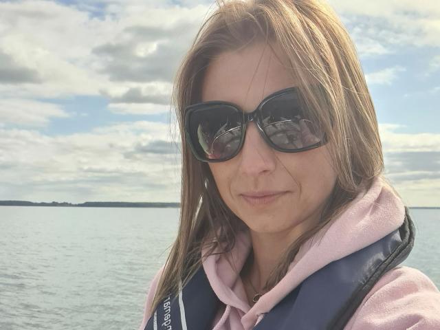 AbenteuerMelody-hot with brown hair, wearing black sunglasses, pink hoodie, and blue life vest, smiling at the camera. She's got a cute nose and a slight smirk.