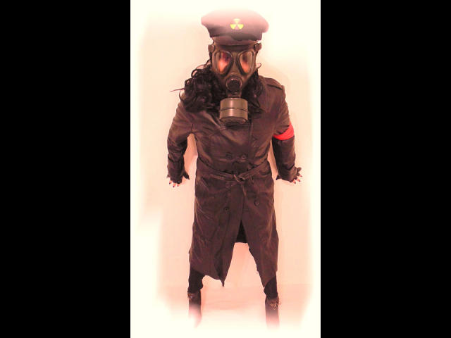 KatarinaArsch-hot in a black military coat, hat with a gold emblem, gas mask, and red armband, standing with arms slightly out, wearing black gloves and boots.